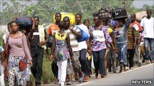 Residents flee with their belongings after clashes between forces loyal to incumbent president Laurent Gbagbo and his rival Alassane Ouattara in Abobo