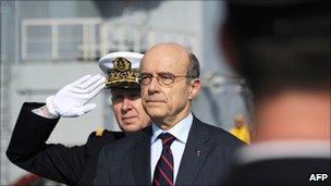 Alain Juppe reviews the troops onboard the Mistral high-tech amphibious helicopter carrier assault and command ship on 18 February 2011