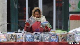 A vendor adjusts pirated DVDs on a street in China