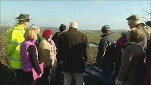Villagers look at the site of the proposed slurry lagoon