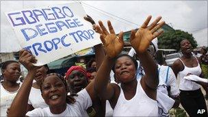 Women carry a sign reading "Gbagbo Leave. Enough is Enough" as they arrive to join an unauthorised protest calling for Laurent Gbagbo to step down on Monday 28 February 2011