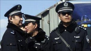 Chinese police officers stand on duty near the Xidan shopping district, one of two sites designated on an Internet call for protest, in Beijing on Sunday