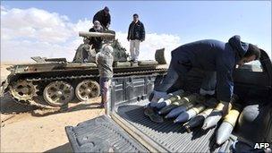 Libyan rebels fill a pick-up truck with shells from an unidentified tank near Ajdabiya on 23 March 2011