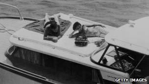Actors Elizabeth Taylor and Richard Burton recline on the deck of a speedboat during a holiday in Ischia, June 1962
