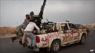 Libyan rebels jump onto the back of their vehicle as they leave Ras Lanuf. Photo: 29 March 2011