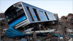 A wrecked train sitting on the ground amid tsunami rubble in Japan