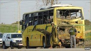 Israeli soldiers stand by a school bus hit by Gaza militants, 7 April