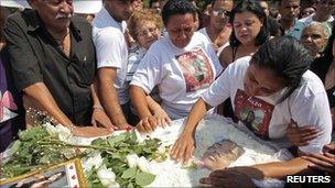 The mother of one of the victims of the Rio school shooting Luiza Paula da Silveira, touches her coffin during her funeral in Realengo cemetery