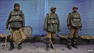 Indian paramilitary soldiers stand in front of shuttered shops during a strike in Srinagar on 11 April 2011