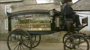 Brynle Williams' coffin passes in a horse-drawn carriage
