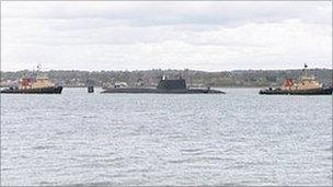 HMS Astute leaving Southampton between two tugs