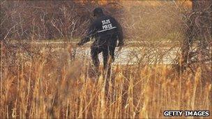 A police officer searches an area near a crime scene on Long Island where the additional remains were found