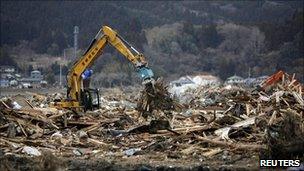 A bulldozer removes remains from destroyed houses