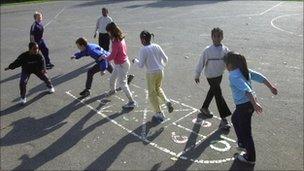 Primary school children playing hopscotch in a playground