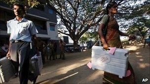 Polling officials carry electronic voting machines to a booth on the eve of elections in Madras (Chennai) on 12 April 2011
