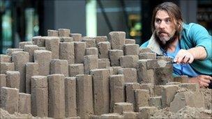 Paul Hoggard shapes his sand sculpture of the Giant's Causeway in Belfast