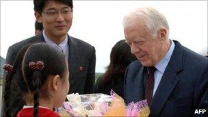 Jimmy Carter receives flowers as he arrives in Pyongyang on 26 August 2010
