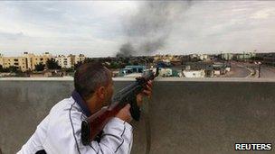 A rebel fires from a rooftop in Misrata, Libya (21 April 2011)