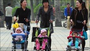 Women push babies in prams through a Beijing park (5 April 2011)