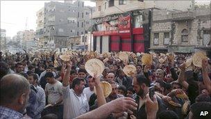 Syrian men carry bread loaves during a protest against President Assad in Baniyas on 3 May (citizen journalism image)