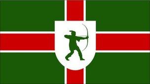 Nottinghamshire flag incorporating St George's cross on a green background, and a shield with the Robin Hood emblem in its centre