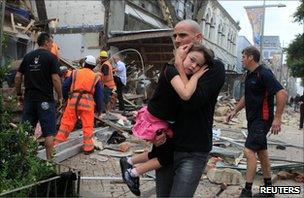 A man in Christchurch carrying a young girl through stricken streets