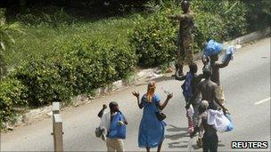 Civilians raise their hands as they walk past a pro-Gbagbo soldier, Abidjan Ivory Coast (April 3, 2011)