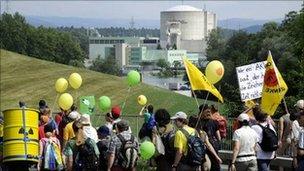 People walk by the Beznau nuclear power plant, the oldest in Switzerland, during an anti-nuclear protest march on 22 May 22, in Doettingen