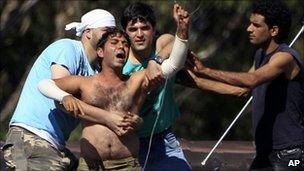 Fellow detainees grab onto a man and removed a wire he had around his neck after he threatened to jump from a rooftop at the Villawood Detention Center in Sydney (April 2011)