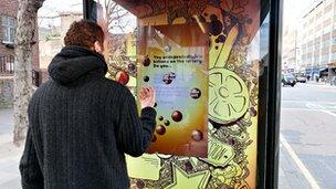 A man plays with one of JCDecaux's interactive bus shelter displays