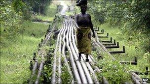 A woman walks along an oil pipeline near in Warri, Nigeria (Archive photograph - 2006)