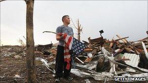 A man prepares to fold an American flag in the devastated city of Joplin, Missouri. Photo: 27 May 2011