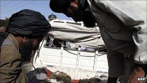 Two Afghan men look down at the bodies of two children (not pictured), said to have been killed in a Nato air strike, at a hospital in Lashkar Gah in Helmand province on 29 May 2011