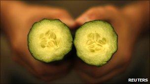 A farmer displays a cucumber cut in half in a greenhouse near Malaga, southern Spain, 29 May 2011