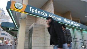 Two men walk past a Bank of Cyprus branch in Nicosia, Cyprus.