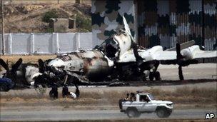 Pakistani troops drive past a destroyed navy warplane at the Mehran base in Karachi (23 May 2011)