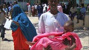 A medical staff member at Medina hospital carries a child injured in a mortar attack in southern Mogadishu on 25 May 2011
