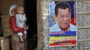 An elderly woman carrying a child stands beside a campaign poster of Andal Ampatuan Snr in Maguindanao, southern Philippines on May 8, 2010