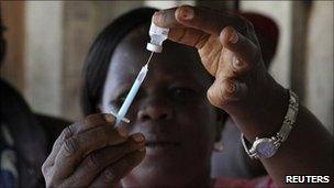 Health worker in West Africa takes a dose of a vaccine