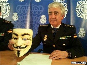 Spanish police officer holds Anonymous mask