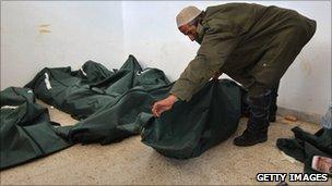 A doctor zips up body bags in Benghazi (25 February 2011)