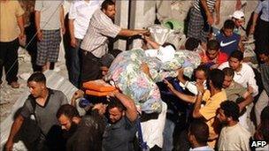 In a picture taken on a government-guided tour, people carry the body of a young man from the rubble of what Libyan authorities say was a Nato air strike in Tripoli, 19 June 2011