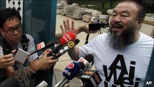 Activist artist Ai Weiwei gestures while speaking to journalists gathered outside his home in Beijing, China on Thursday