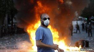 Protester stands before a fire on Syntagma Square in Athens