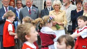 The Prince of Wales and the Duchess of Cornwall watch folk dancing by children from Ysgol Rhys Prichard primary school at Llandovery railway station