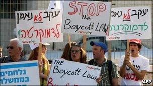 Israeli demonstrators hold up signs calling for a halt to the boycott bill