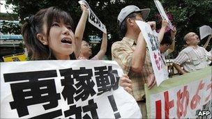 People shout slogans as they hold banners during an anti-nuclear power plant rally in front of the Tokyo office of Kyushu Electric Power Co, in Tokyo on July 8, 2011