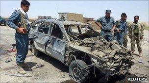 Security forces by a bomb-damaged car in Kunduz, Afghanistan (19 June 2011)