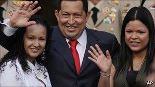 Venezuela's President Hugo Chavez, waves flanked by his daughters Rosa Virginia (R) and Gabriela, after he announced he would return to Cuba Saturday to begin a new phase of cancer treatment that would include chemotherapy