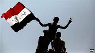 Protesters wave the Egyptian national flag as they perch on top of a street lamp in Tahrir Square in Cairo, Egypt, Friday, 15 July 2011